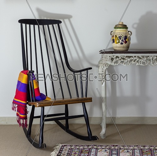 Classic rocking chair and old style vintage table on background of off white wall